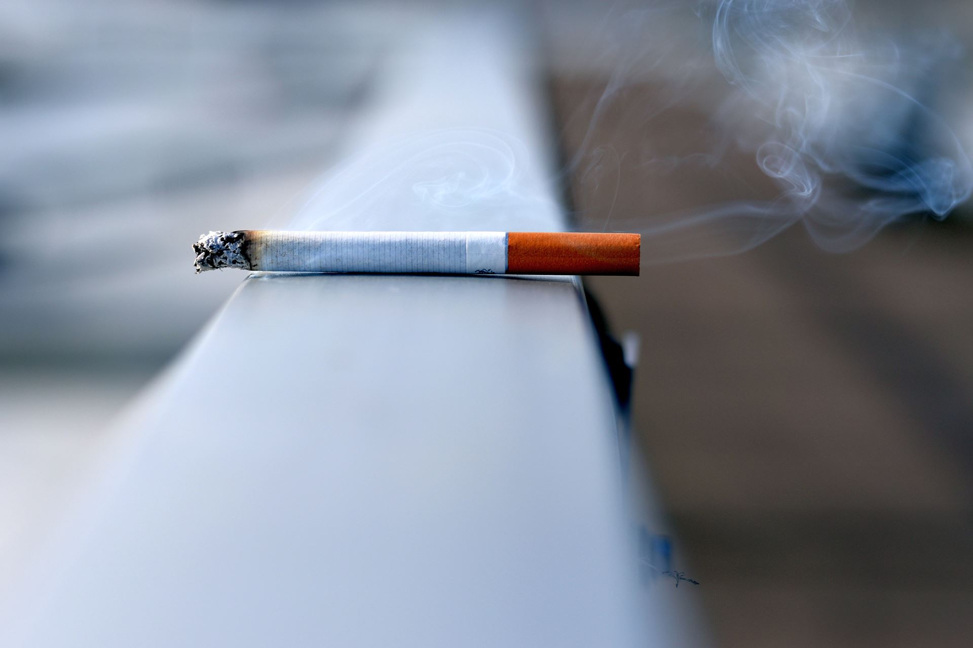 A cigarette lying on a railing