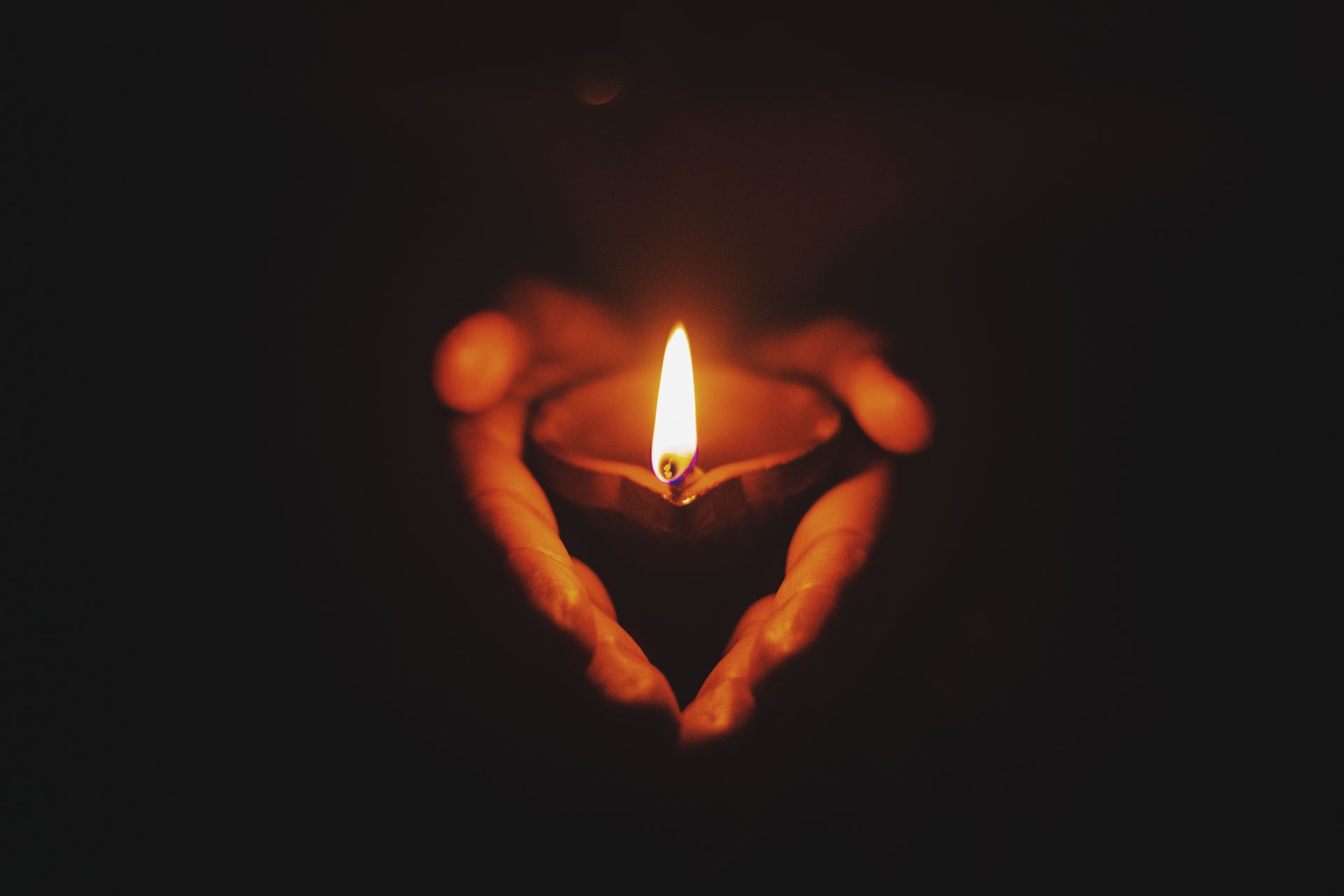 A tealight candle held in cupped hands