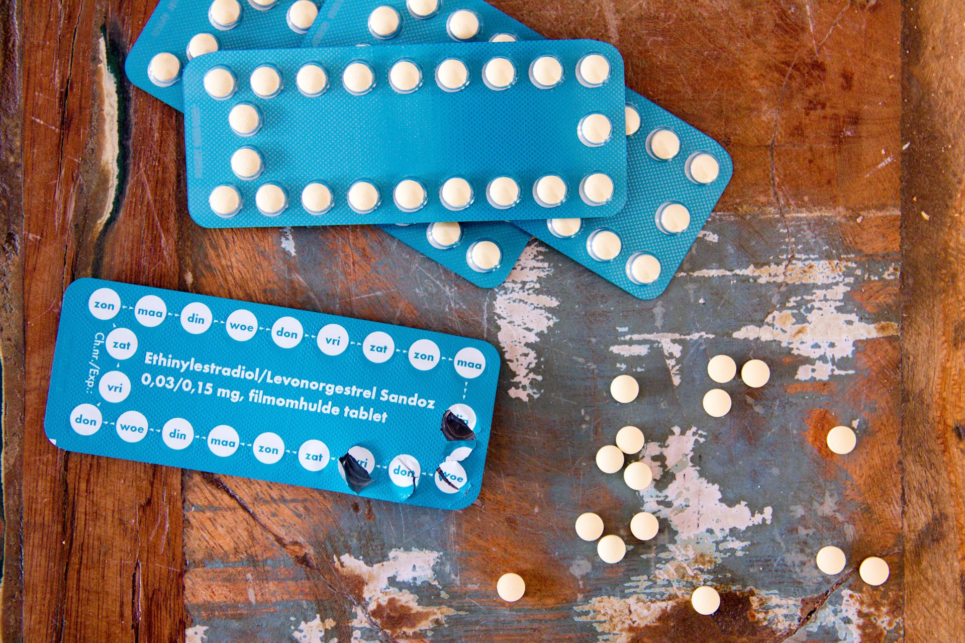 Some contraceptive pills in their packets on a wooden surface